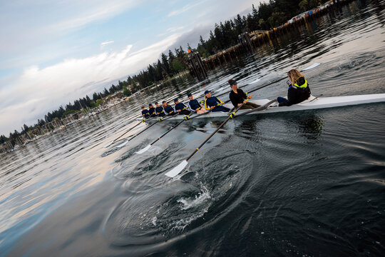 A white women's rowing team practicing rowing on calm coastal waters