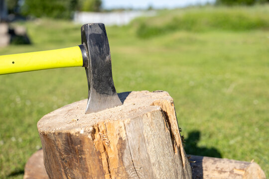 Close-up of axe stuck in log outdoors during summer daytime