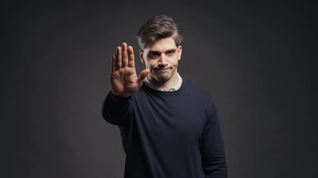 Serious Young Man In Classic Outfit Showing Firm Stop Palm Gesture Toward Camera, Male Rejecting An Offer Or Request, Refusal, Warning, Boundaries, Ban And Disagreement