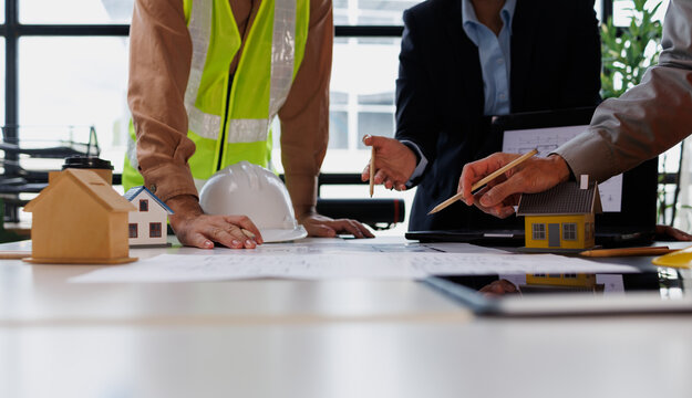 Construction team and real estate professionals analyzing blueprints and architectural drawings, planning future home building