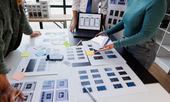 Ux ui designers collaborating on user interface development, analyzing wireframes and app prototypes for digital experience