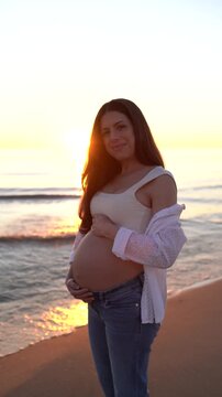 Pregnant Woman Cradling Her Baby Bump on the Beach at Sunrise