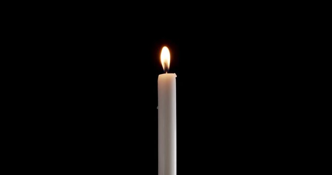 Moody candle on a black background. Watch how the flame of the candle slowly flickers. This glowing candle is ideal for background or over-layer with blending mode add, screen, lighten.