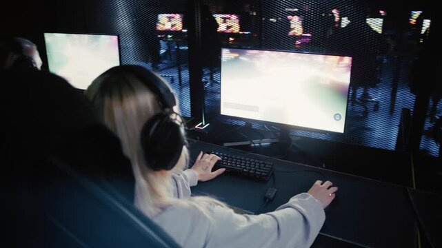 Young woman playing a video game at a computer club during an esports competition with her team