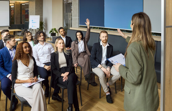 Speaker engages audience team training seminar meeting. Coach presents to office professionals as a manager invites questions with raised hands and notebooks. Concept of teamwork and leadership.