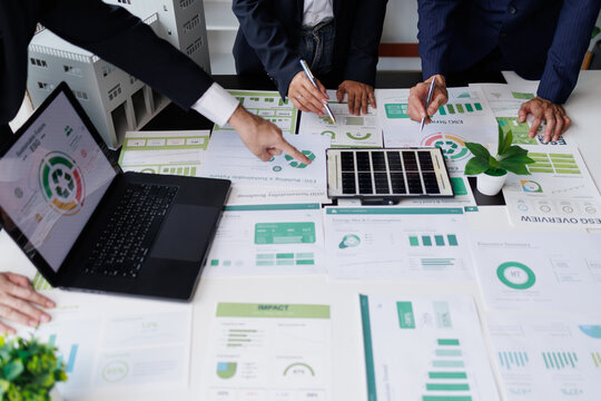 Business people analyzing esg reports on sustainability, green economy, and environmental impact strategies, using data on laptops and papers