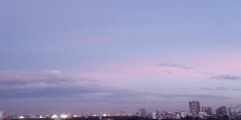 Fototapeta premium Twilight city skyline with soft pink clouds over urban landscape at dusk