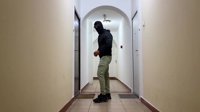 Home burglary. Masked burglar attempting to break Into apartment door in residential building hallway. 4k video animation