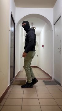 Home burglary. Masked burglar attempting to break Into apartment door in residential building hallway. 4k video animation
