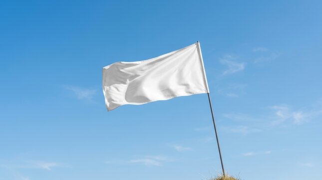 A blank white flag waving against a clear blue sky.