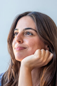 Young woman portrait looking thoughtfully into the distance with a soft smile, close-up headshot conveying calm, optimism and daydreaming