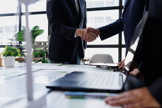 Business people shaking hands, closing deal, establishing partnership, and cooperating on corporate strategy in office meeting