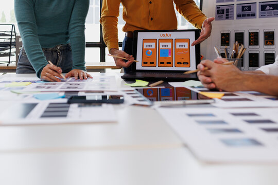 Uxui designers collaborating on a new mobile application interface, discussing wireframes and app prototypes