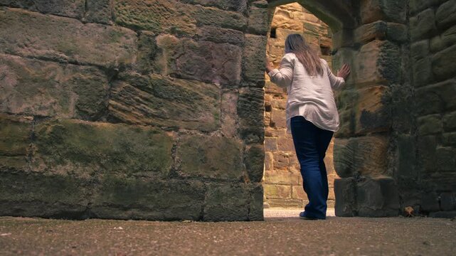 Tourist exploring ruins of old monastery archway at Monk Bretton Priory in Yorkshire