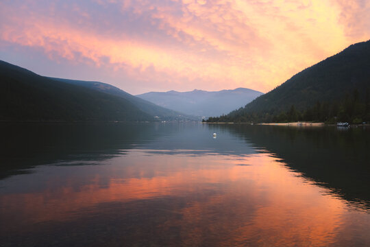 Colourful sunset sky over the still West Arm of Kootenay Lake and Nelson BC, Canada on a summer evening.
