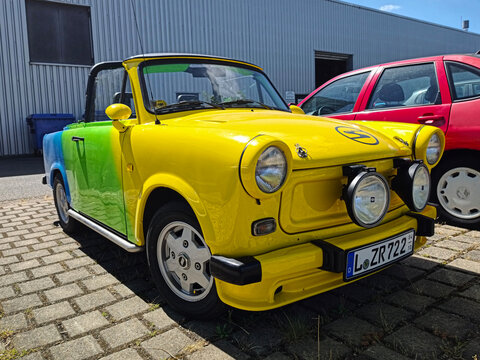 Leipzig, Germany - August 11 2026 Modified Trabant 601 Cabriolet parked in a lot. The car features a colorful paint job blending yellow, green, and blue. 