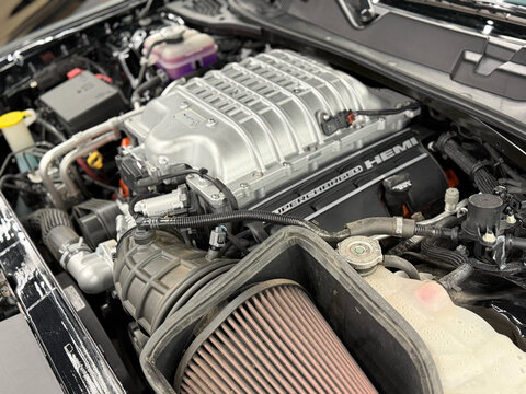 Detailed view under the hood of a car with a supercharged V8 HEMI engine bay and cold air intake system, high performance modified automobile motor closeup, automotive mechanical engineering concept. 
