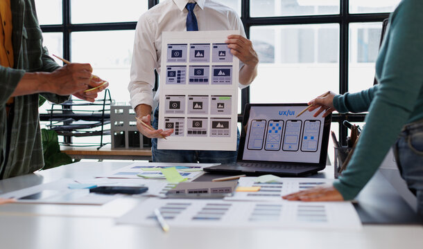 Ux ui designers collaborating on web development and app interface wireframes during a creative team meeting
