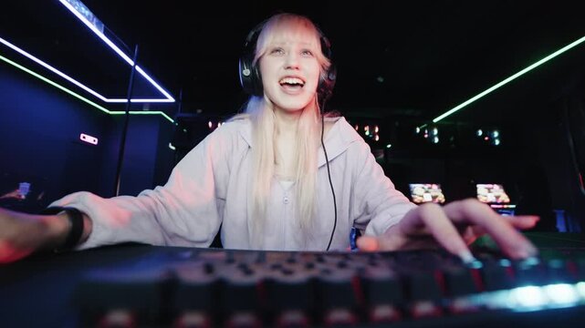 Professional woman gamer celebrating winning an online video game in a neon-lit computer club