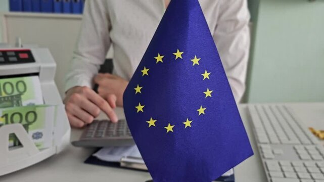 Working with a cash register and an EU flag in an office setting