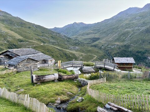 Alpine stone cottages and wooden bridge over mountain stream