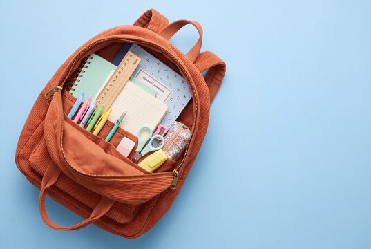 High-angle stock photo of an open backpack with school stationery and notebook supplies arranged neatly for study planning