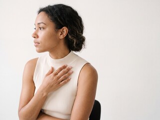 Obraz premium Thoughtful young woman with hand on chest in a calm wellness portrait, conveying empathy, concern, reflection, and self-care