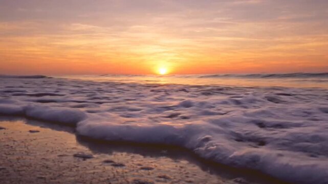 Beautiful ocean waves gently rolling onto sandy beach at sunset with golden sun reflecting on wet sand, peaceful tropical seascape motion footage.
