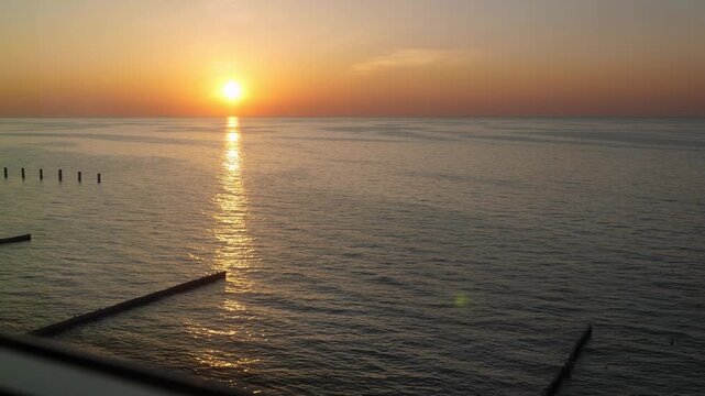 Glass lift elevator moving up. View to sunset on sea beach through transparent window