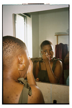 Woman looking in the mirror while applying makeup