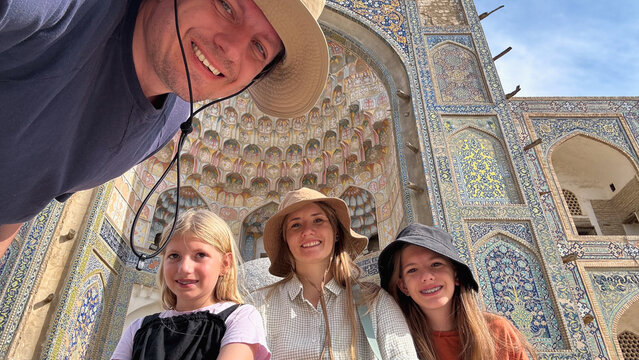 Family of four taking a selfie in front of Abdulaziz Khan Madrassah.