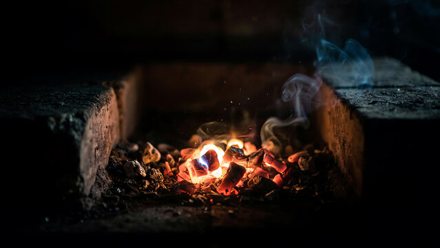 Glowing campfire with burning logs inside rustic brick fire pit during nighttime outdoor gathering