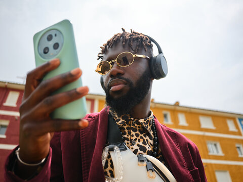 Young black man connecting using smartphone headphones