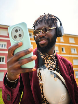Black man taking selfie with smartphone in urban setting