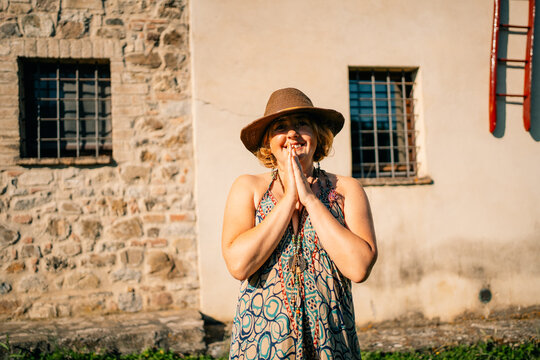 Woman Expresses Joy Outdoors Near a Stone Building in Sunny Weather