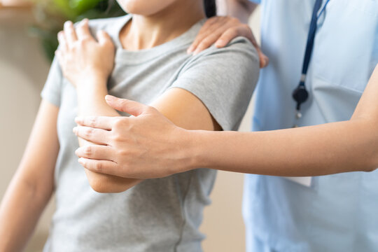 Asian young woman physical therapist guiding a patient through arm and shoulder extension exercises for joint rehabilitation, office syndrome relief and occupational therapy concept.
