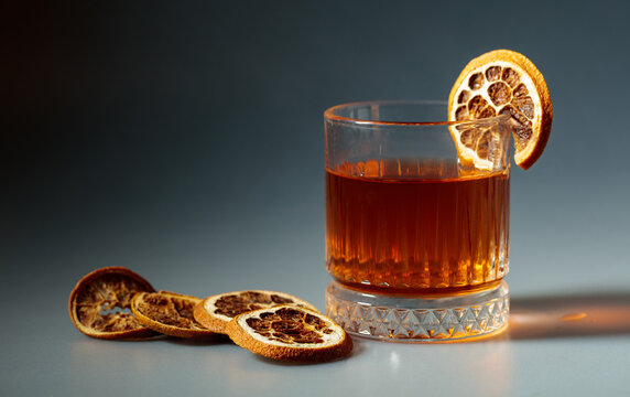 Refreshing rum cocktail garnished with dried orange slice.