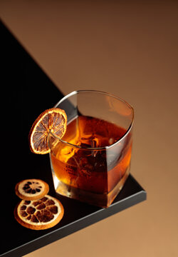 Old-fashioned cocktail with ice and a dried orange slice.