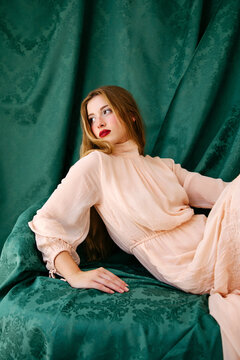 Woman reclining on green drapery