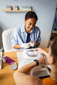 Smiling nail technician preparing a client's nails