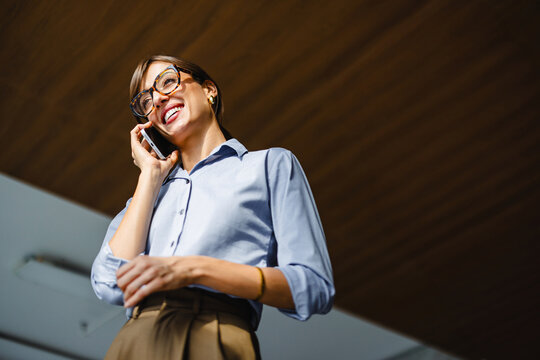 Woman Talks on Phone in Office Setting During Work Hours