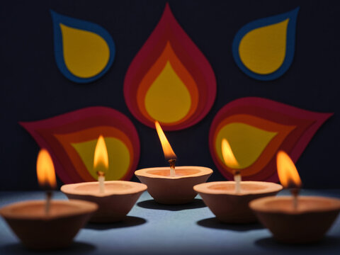 Clay diyas with flickering flames illuminate a festive backdrop