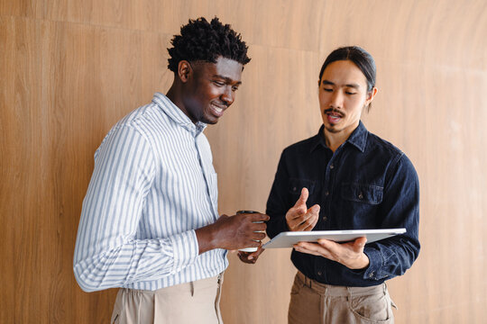 Two Men Discuss Ideas While Looking at a Tablet in a Workspace