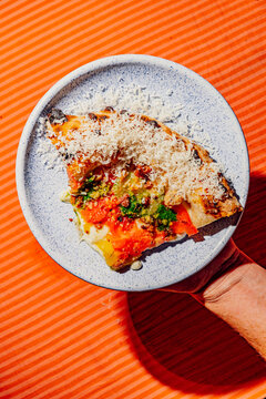 Hand holding a gourmet pizza slice 