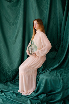 Woman in pink dress holding vintage glass bottle