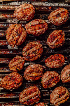 Spiced kofte meat patties cooking on a charcoal grill
