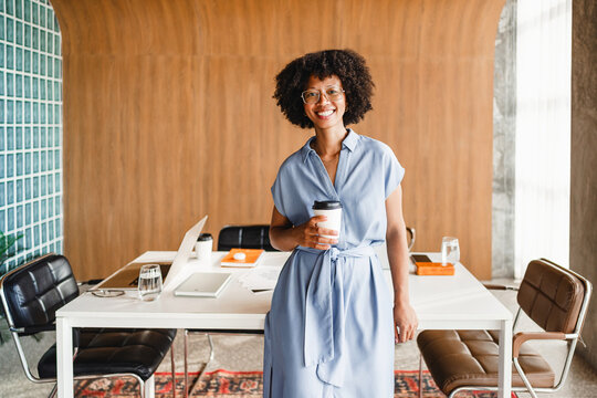 Smiling Person Stands With Coffee in Modern Office Setting