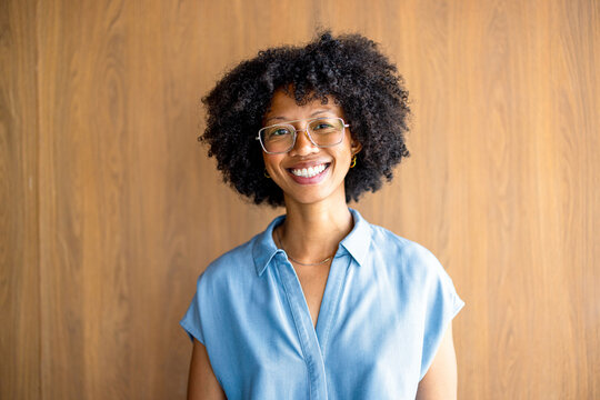 Smiling Woman Stands in Front of a Wooden Wall in Bright Light