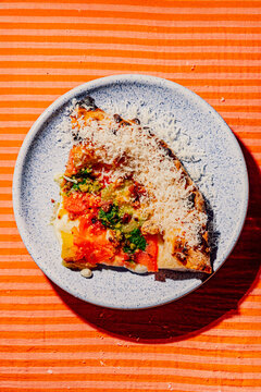 Gourmet pizza slice with grated parmesan on a ceramic plate