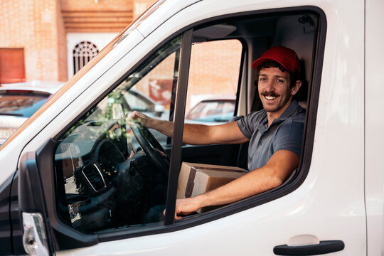 Smiling delivery man driving van with package